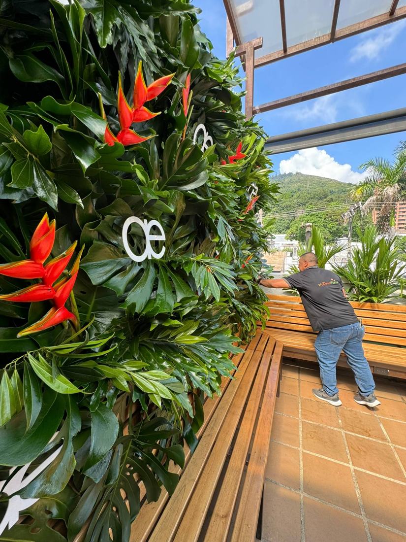 Muro verde con heliconias y el logo del cliente