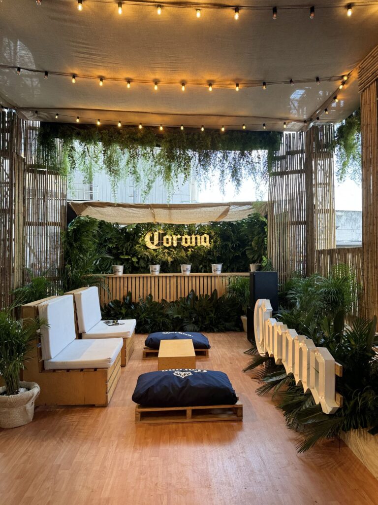 Lounge para una marca de cerveza con techo de follajes y muro verde