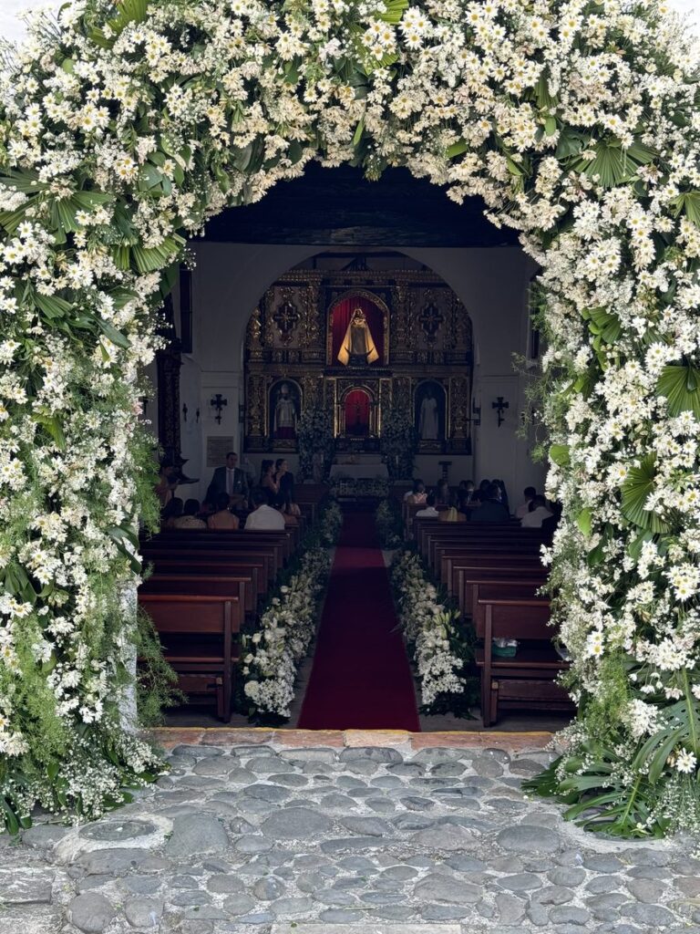 Arco de flores blancas en la entrada de una iglesia