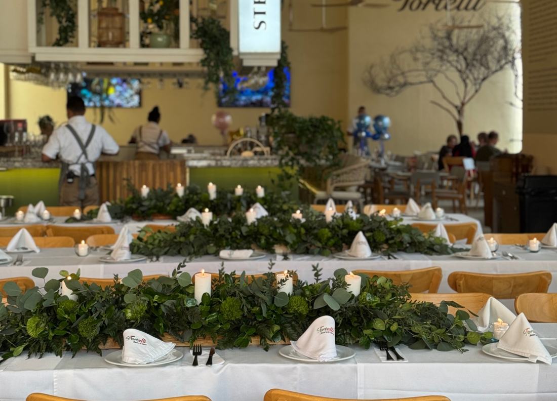 Mesas de evento con caminos de follaje y velas en Tortelli
