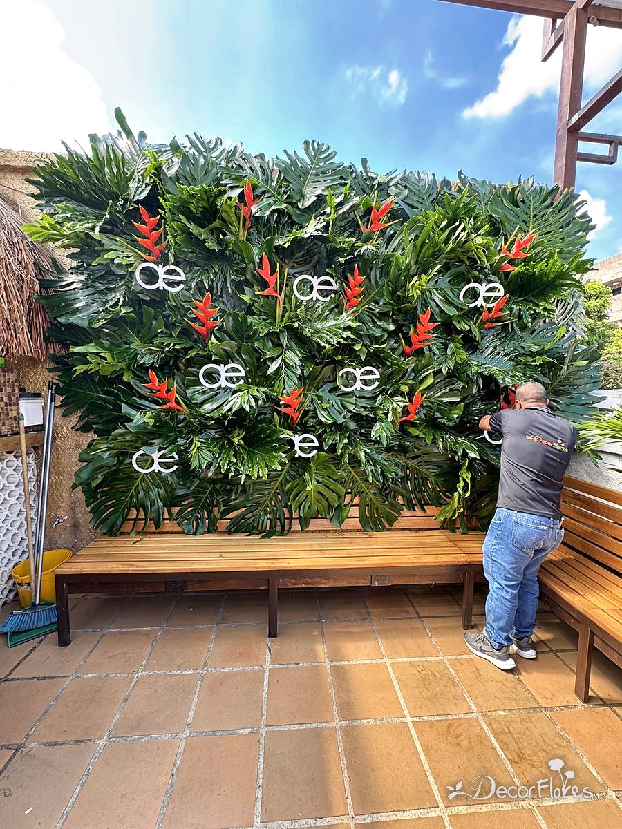 Después: muro verde con heliconias y el logo del cliente